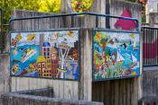 Two colorful tile mosaics depict scenes from Mercer Island and Seattle life, installed on a concrete wall in a park playground.