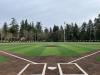 View from behind home plate on a baseball diamond featuring green and brown synthetic turf